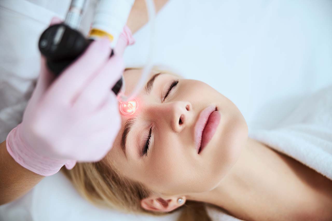 Woman having laser treatments for forehead wrinkles Effective laser wrinkle treatment for smooth, youthful skin.