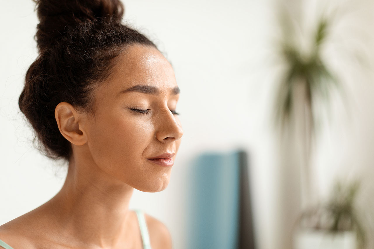 woman with closed eyes indoors practicing mindfulness Woman practicing mindfulness for effective weight loss management.