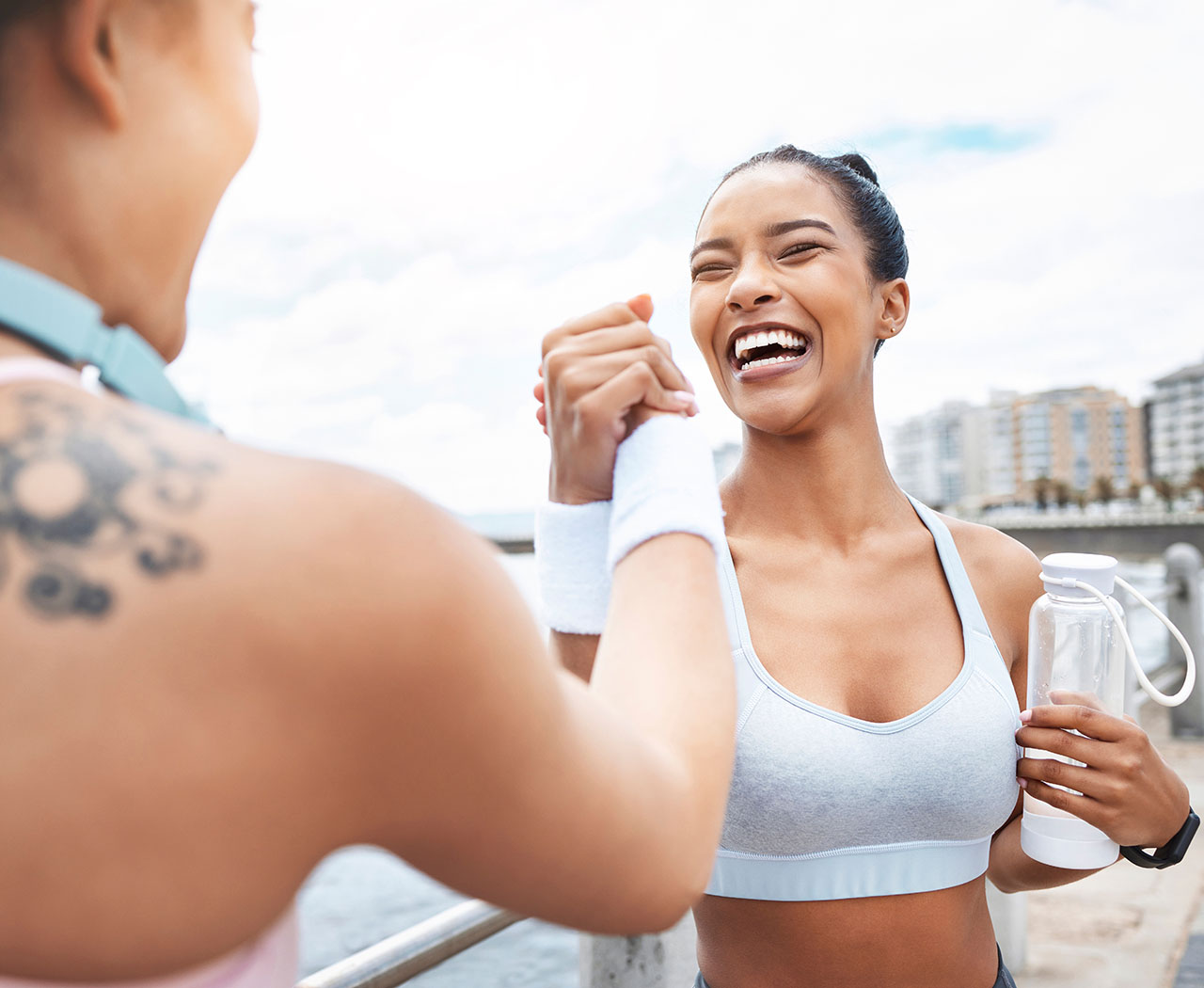 women congratulating each other on their workout at the beach Post-workout joy, illustrating the energy supported by vitamin therapy and nutraceuticals.